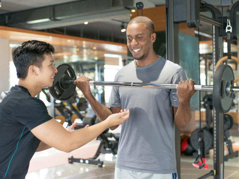 Trainer correcting a beginner’s workout form to avoid mistakes