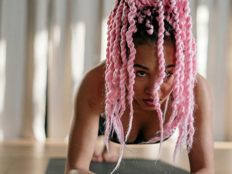 Beginner woman doing a plank at home on a yoga mat to build core strength.