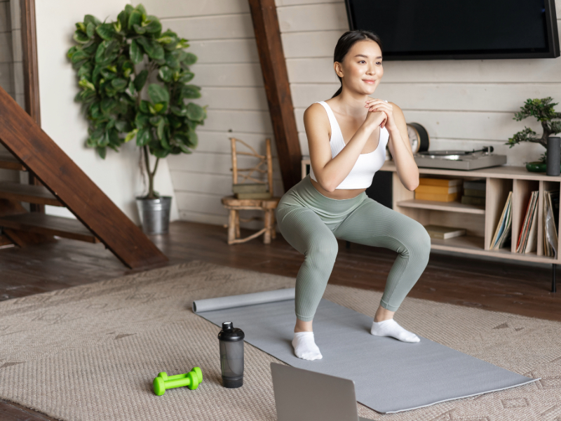 Beginner performing bodyweight squats with proper form at home